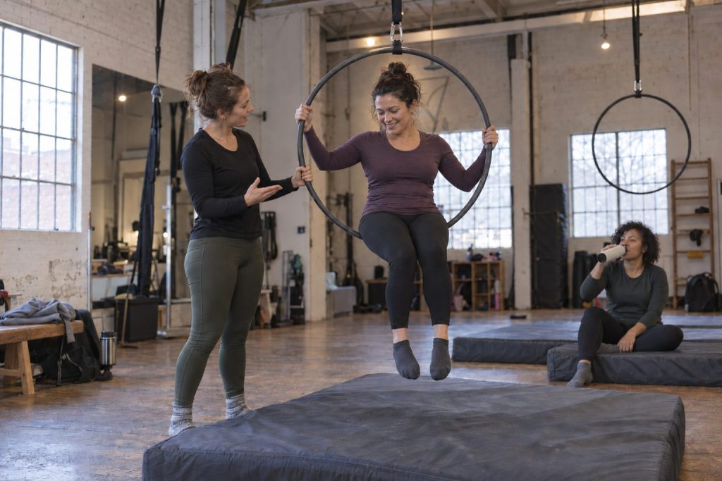 A beginner sits in a low lyra hoop while her instructor explains the next move